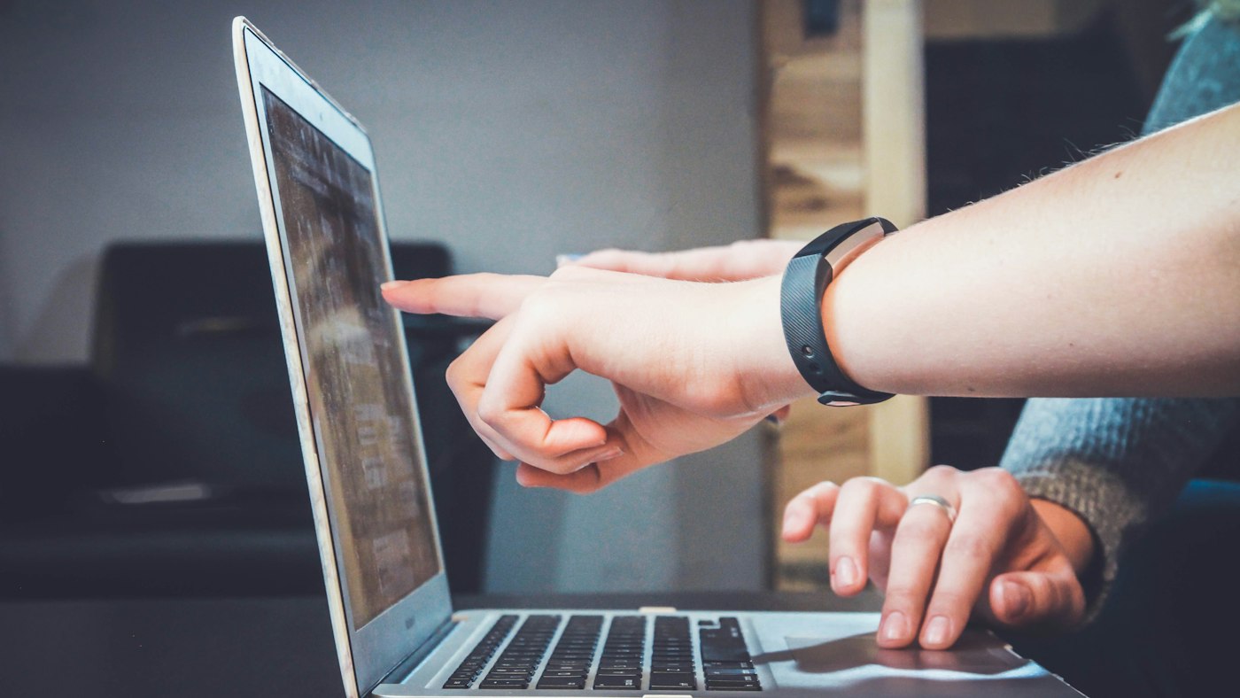 Two people pointing at a laptop screen together